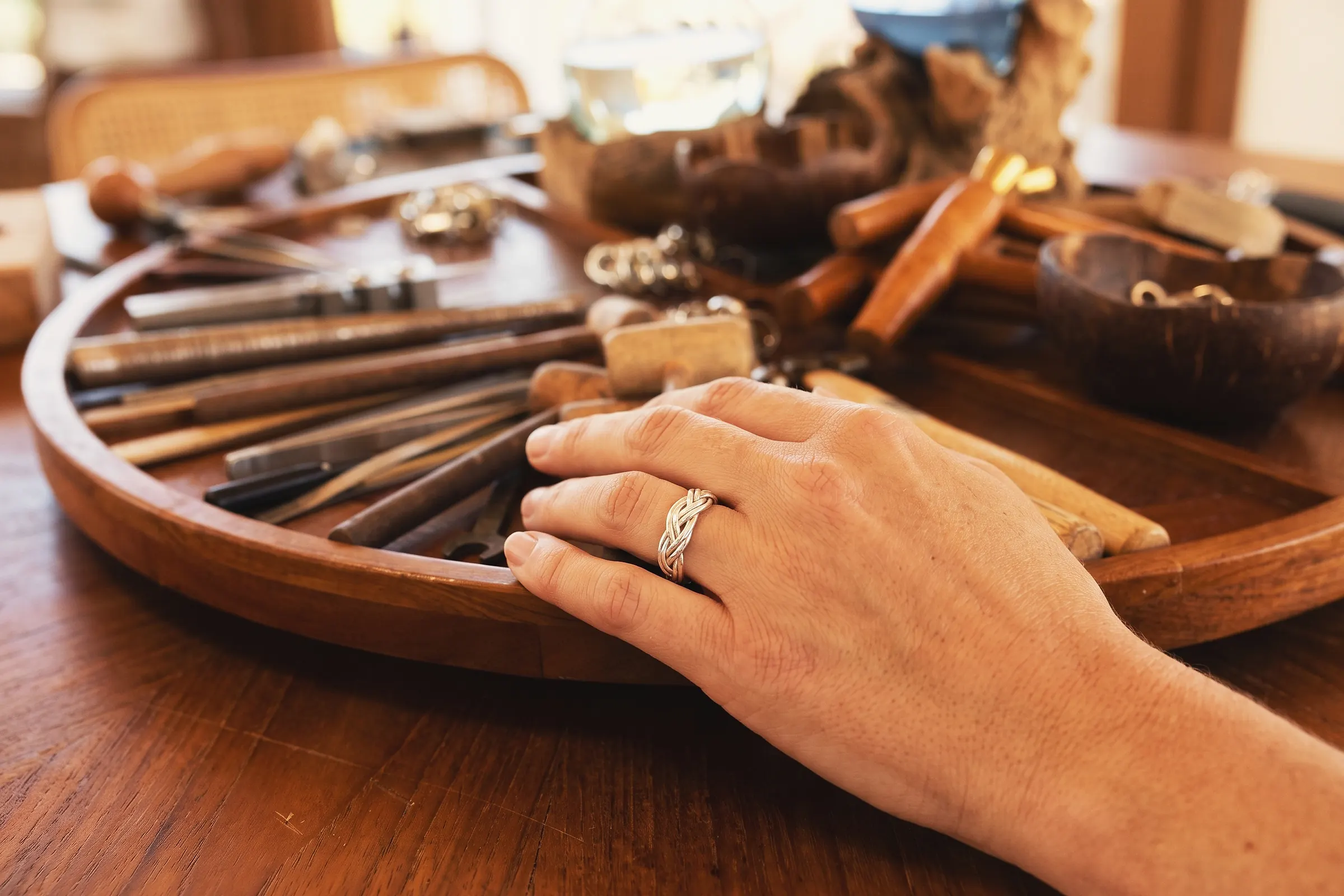 A braided silver ring made in the Silver Class, worn at the teak workbench