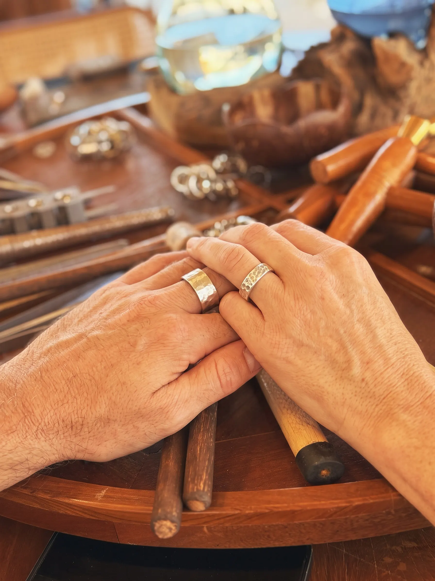 Two hands together, each wearing a hammered silver ring made in the Couple Silver Class